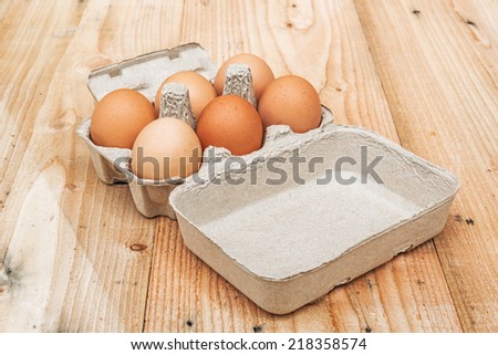 Brown chicken eggs in the package on wood background