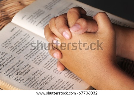 Hands clasped in prayer on Holy Bible