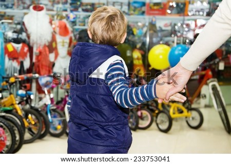 Mom firmly holding the baby by the hand in a toy store