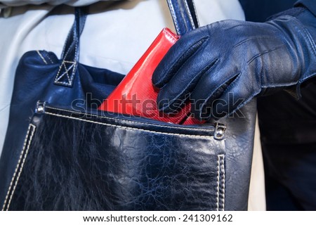 Thief in gloves stealing a purse  from the women\'s bags