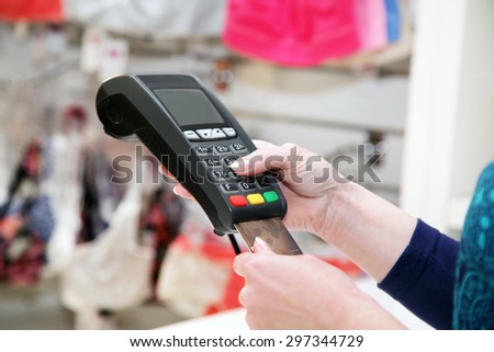 Close-up  hand holds  terminal and credit card in store