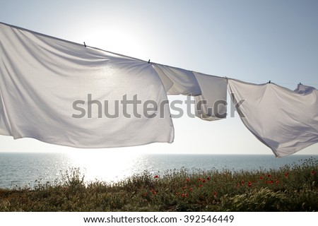 White clean sheets outdoors. Drying on a rope on background of beautiful scenery in the sun