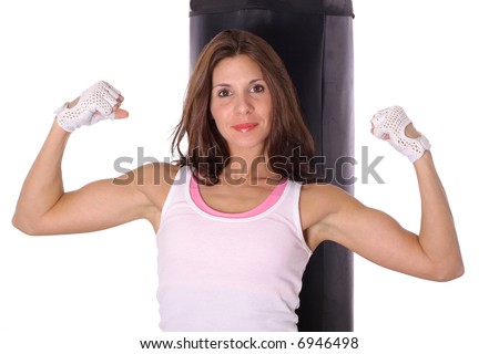 Fitness girl flexing in front of punching bag