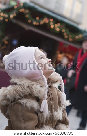 Little girl looking up on christmas market