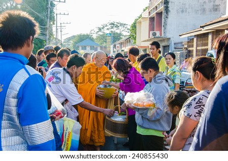 LOPBURI, THAILAND - JANUARY 1:Thai people give food offerings to a Buddhist monk on 1 January, 2015 in Lopburi, Thailand. Buddhist Thai traditional, people will make merit making by give food to monk.