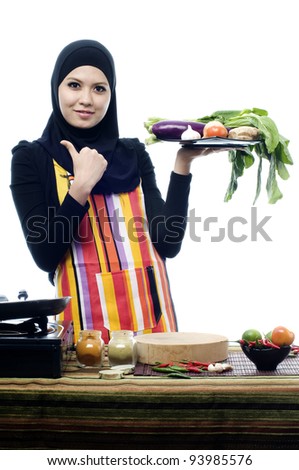 Beautiful muslim woman wearing scarf holding vegetables and show thumbs up isolated white background