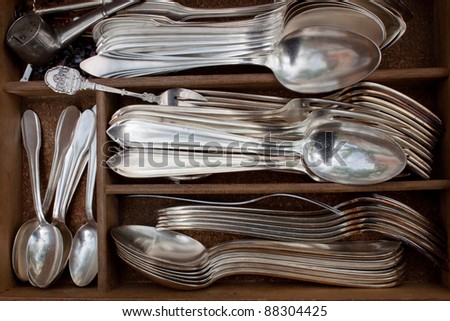 old silver spoons, teaspoons and forks in a box on a flea market