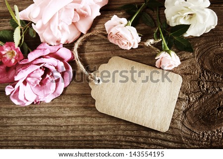 Handmade paper tag with string and roses on a rustic wooden table