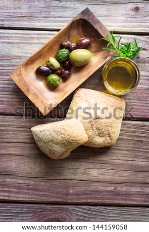 Assorted pickled olives with bread and olive oil on a rustic wooden table