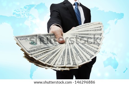 Business Man Displaying Spread of Cash over World Map
