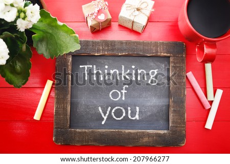 Thinking of You message written on a little chalkboard on a red wooden board