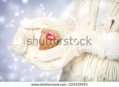 Small handmade gift box in womans hands with white gloves in the snowing night