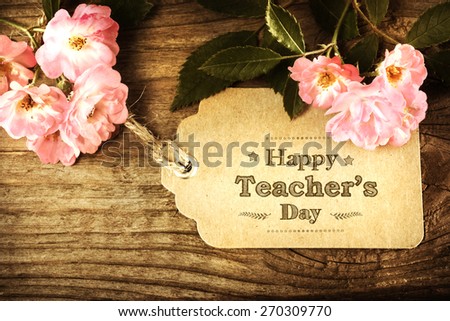 Happy Teachers Day message with small pink roses on rustic wooden table