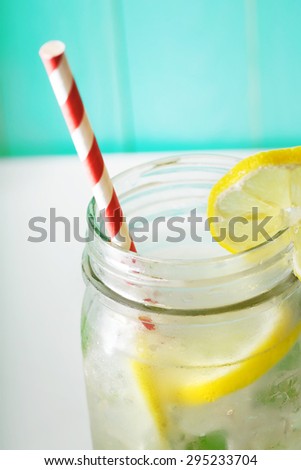 Homemade lemonade in a mason jar with big red striped straw