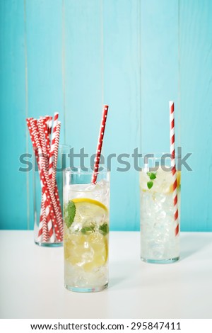 Homemade lemonades with assorted big red paper straws on pastel blue background