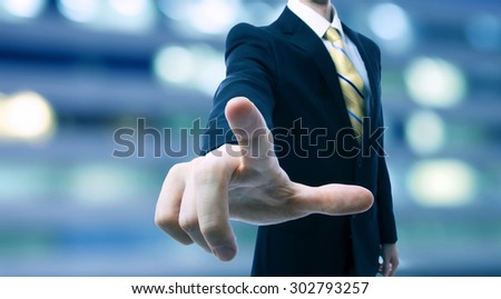 Businessman touching a touch screen on blurred city background