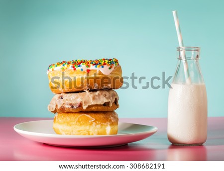 Stack of donuts with milk in a jar on pastel pink and blue background