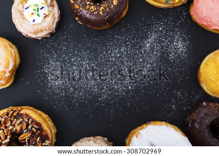 Assorted donuts with powder flour on black background