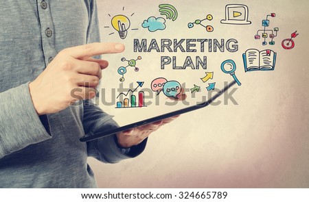 Young man pointing at Marketing Plan concept over a tablet computer