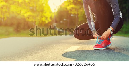 Female runner tying her shoes preparing for a run a jog outside