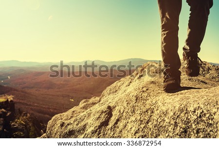 Man walking on the edge of a cliff high above the mountains below