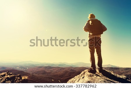 Man standing at the edge of a cliff overlooking the mountains below