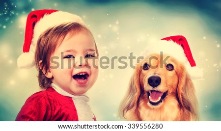 Happy Toddler girl and Dachshund dog with Santa hats smiling