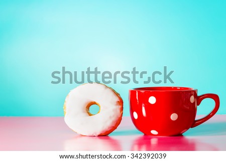 White donut with big red mug on a pastel blue and pink background