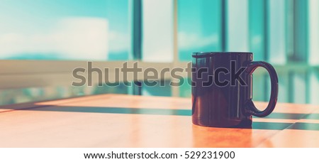 Black cup of coffee in brightly lit modern interior