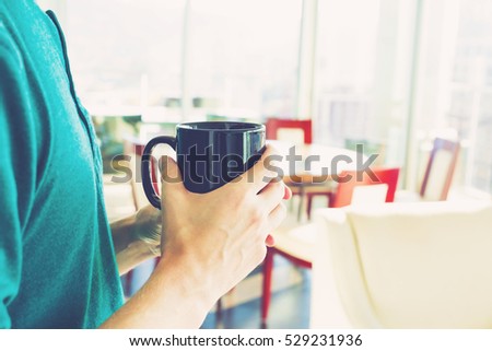 Young man with a cup of coffee in a brightly lit modern interior room