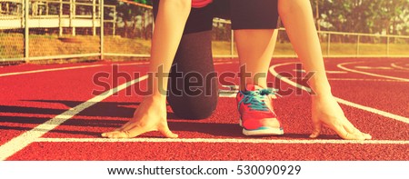 Female athlete on the starting line of a stadium track preparing for a run