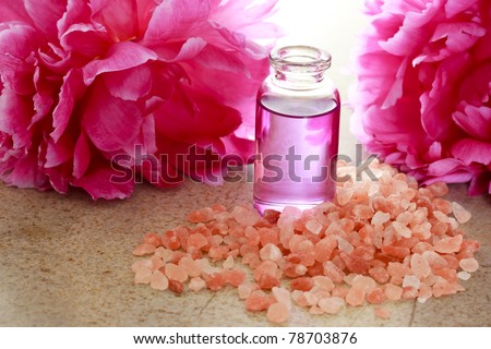 Aroma oil in bottle with pink peony flowers and bath salt