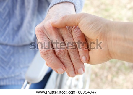 Young woman holding senior woman\'s hand