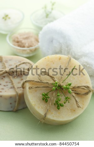 Bars of soap with bath salt and towels in light green background