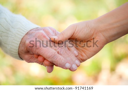 Senior and young holding hands outside