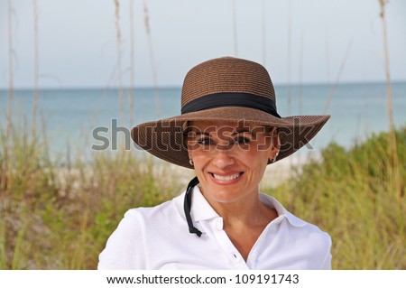 Attractive Middle Aged Woman Wearing a Sun Hat Standing on the Beach