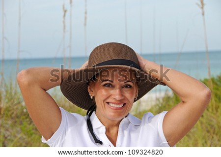 Attractive Middle Aged Woman Wearing a Sun Hat Standing on the Beach