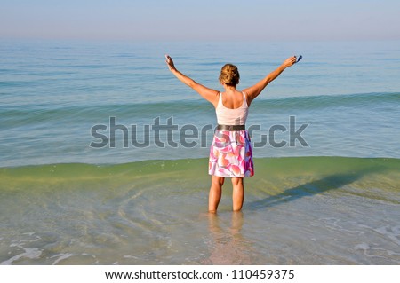 Attractive Middle Aged Woman Standing in the Ocean With Her Arms Held Up