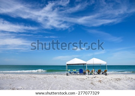 Two Portable Canopy\'s with Lounge Chairs set up to provide shade on the Beach