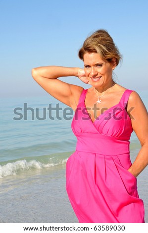Attractive Middle Aged Woman on Beach in a Pink Summer Dress