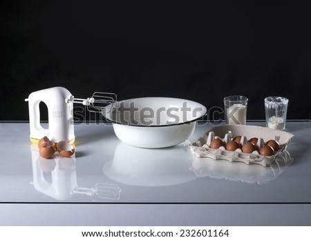 Photo of a cooking still-life with mixer, flour, eggs, sugar, bowl.