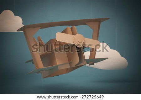 Hand made airplane made of cardboard on blue sky with paper clouds.