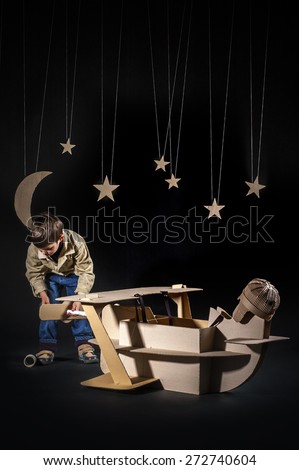 Young aviator assembling corrugated plane on the dark night sky background