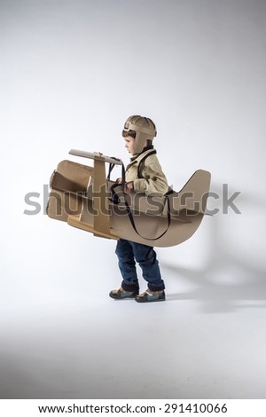 Young pilot is flying on cardboard airplane.  Side view.