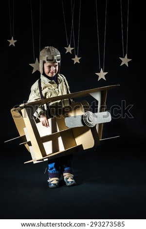 Boy is playing with handmade toy plane. Decorations of night sky is on background.