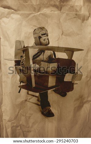 Young aviator in a homemade cardboard aircraft. biplane. photo on crumpled paper.