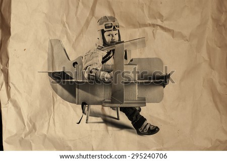 Young aviator in a homemade cardboard aircraft. biplane. photo on crumpled paper.