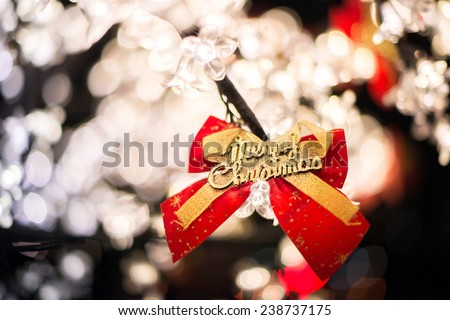 Merry Christmas tree with plenty of lights and decorations red color bow with golden letters.