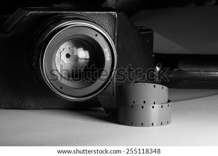 Film strips closeup with vintage movie cinema camera with lens on background
