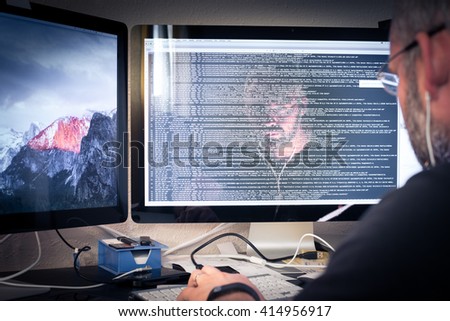 Hacker or software program developer working with computer face reflection in the monitor with code